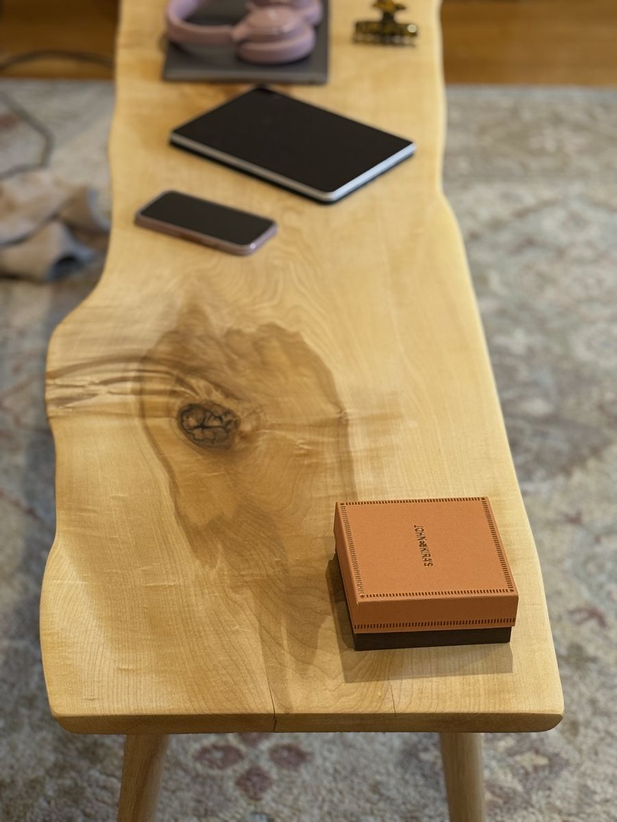 Looking down the length of the pale live-edge coffee table, past a large knot with dark figure radiating from it.