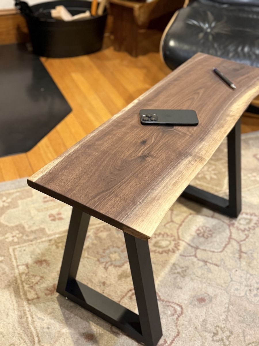 The walnut bench top from one end, with a phone and pen resting on it to show scale.